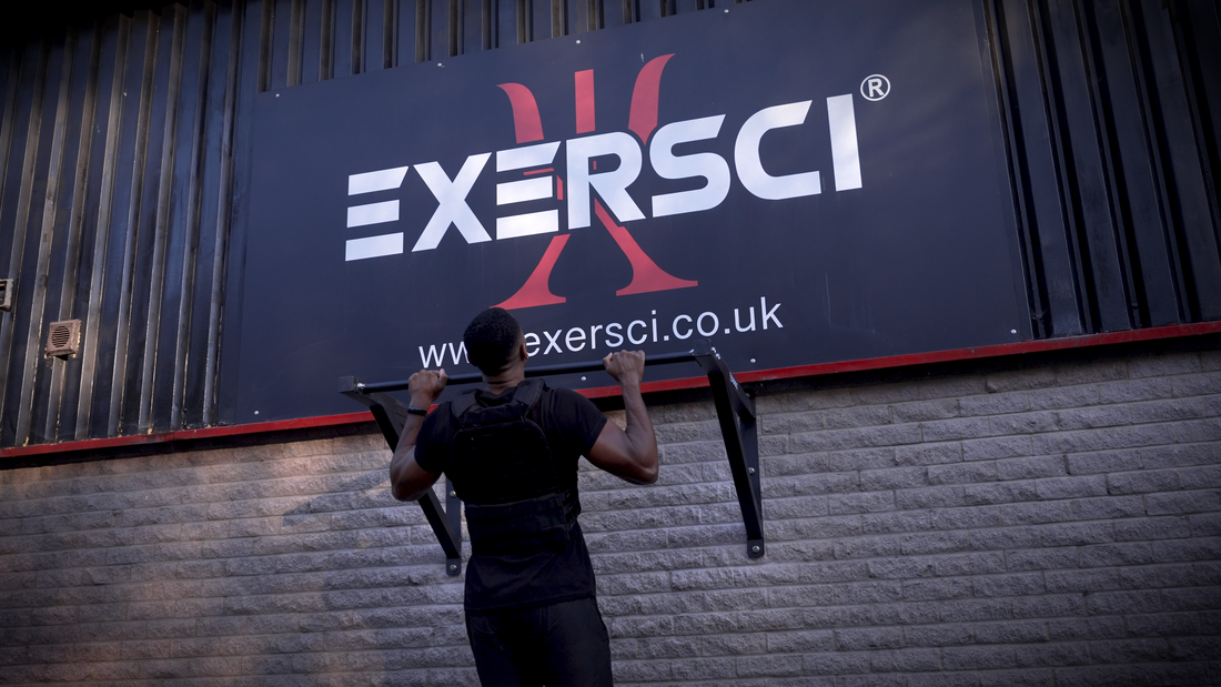 A man completing a pull up with a weighted vest on in front of an Exersci banner to illustrate the blog entitled 'The Complete Guide To Cutting - How To Loose Fat And Maintain Muscle'