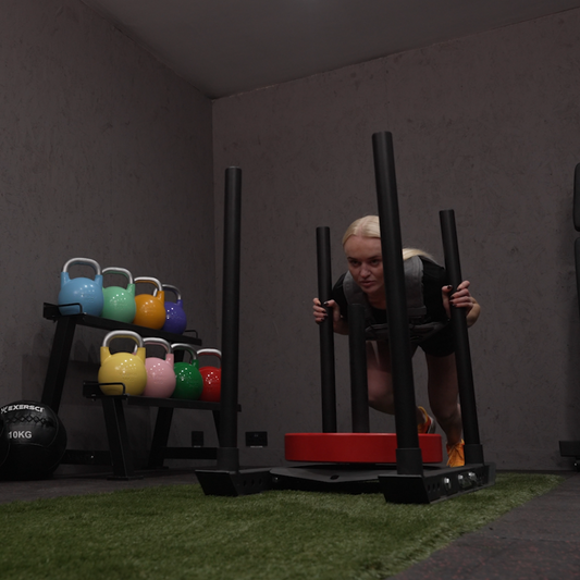An image of a woman pushing the Exersci® Weight Plate Sled to illustrate the Exersci blog post entitled 'Sled Push vs Sled Pull: Which is Better for Strength & Fat Loss?'