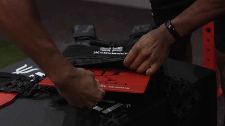 An image of a man inserting weighted vest plates into an Exersci branded weighted vest to illustrate the Exersci blog post entitled 'Are Weighted Vests Good For Weight Loss?'