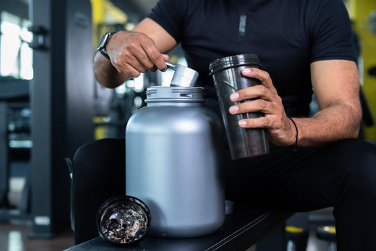 Bodybuilder mixing protein powder with water to make protein shake to illustrate the Exersci blog entitled 'Cheap and Effective Weight Lifting Supplements | A Guide'