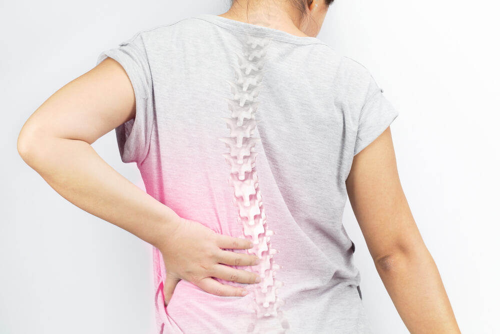 A woman grabbing her lower back in pain. This image is to illustrate the Exerscie blog entitled 'Are Weighted Vests Good For Osteoporosis?'