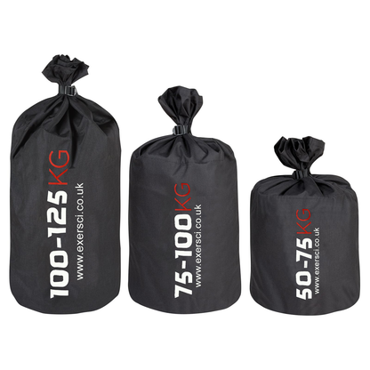 Three black Exersci strongman sacks in different sizes with weight labels indicating 50-75kg, 75-100kg, and 100-125kg.