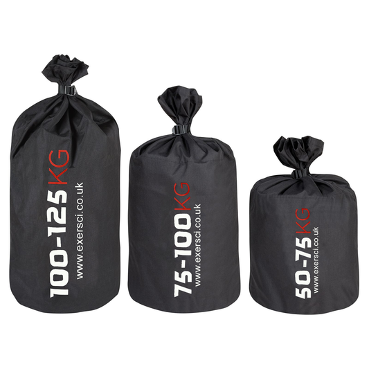 Three black Exersci strongman sacks in different sizes with weight labels indicating 50-75kg, 75-100kg, and 100-125kg.